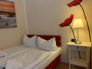 um quarto com uma cama com uma flor vermelha numa mesa em MPH - Whg 14 em Wyk auf Föhr