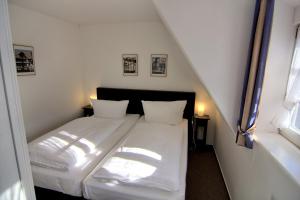 Schlafzimmer mit einem Bett mit weißer Bettwäsche und einem Fenster in der Unterkunft Apartment mit Balkon No5 in Quedlinburg