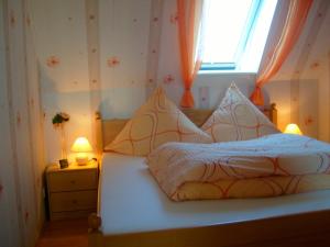 a bedroom with a bed with two lamps and a window at Haus Monika in Büdelsdorf
