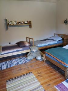 a teddy bear sitting on the floor in a bedroom at Bakancstanya in Kétbodony