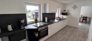 a kitchen with white cabinets and a black counter top at Ferienwohnung Peters in Adendorf bei Lüneburg in Adendorf