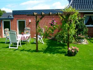 a garden with a table and chairs and a pergola at Haus Monika in Büdelsdorf