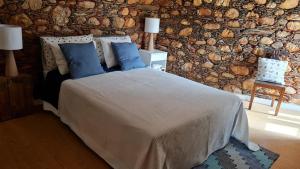 a bedroom with a bed with blue pillows and a stone wall at Casa da Ti Adélia in Janeiro de Cima