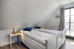 a white bedroom with two beds and a window at Sanya in Zingst