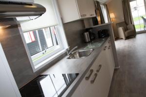 een keuken met witte kasten, een wastafel en een raam bij Chalet bis 5 Personen ohne Hund - a17099 in Norden