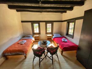 zwei Betten in einem Zimmer mit Tisch und Stühlen in der Unterkunft House of Sokolovi Kratovo in Kratovo