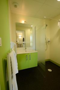 a green bathroom with a sink and a shower at Hôtel la Verriaire - The Originals in La Verrie