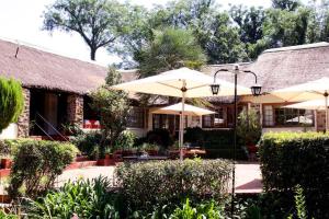 a resort with tables and umbrellas in a courtyard at Sandford Park Country Hotel in Bergville