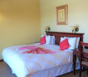 a bedroom with a large bed with red pillows at Sandford Park Country Hotel in Bergville