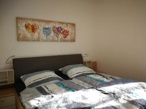 un letto con due cuscini e una foto sul muro di Komfort-Wohnung 03 FehmarnBrise a Burg auf Fehmarn