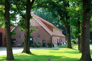a red brick building with trees in front of it at Ferienhof Westermann Eulennest in Herßum
