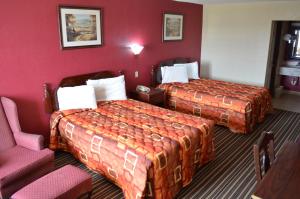 a hotel room with two beds and a chair at Royal Inn Greenville in Greenville