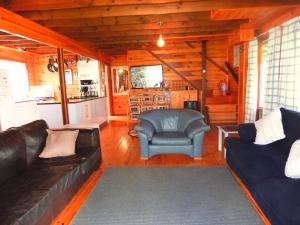 a living room with two couches and a kitchen at Ashanti House - Living The Breede in Malgas