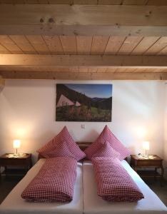 Schlafzimmer mit einem Bett mit roten und weißen Kissen in der Unterkunft Ferienwohnung Belchenliebe in Schönenberg