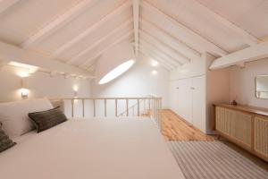 Großes weißes Zimmer mit einem Bett und einem TV. in der Unterkunft Tripas Coração Taipas Historical Center in Porto