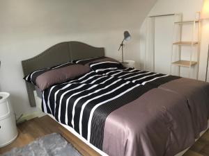 ein Bett mit einer schwarz-weißen gestreiften Bettdecke in einem Schlafzimmer in der Unterkunft Comfortapartment LEONDING in Leonding