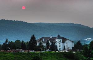 uma grande casa branca com uma montanha ao fundo em AX Hotel em Mont-Tremblant