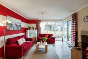 una sala de estar roja con 2 sofás rojos y una mesa. en Wellness - Bungalow Strandgut en Klausdorf