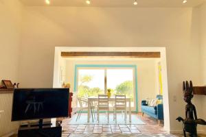 een woonkamer met een televisie en een tafel met stoelen bij Villa-Golfe de Saint-Tropez/Accès plage privée in Grimaud