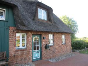 a thatch roofed house with a green door at Nordseekrabbe 12 Herrenhof in Wrixum