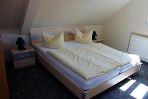 Schlafzimmer mit einem Bett mit weißer Bettwäsche und Kissen in der Unterkunft Ferienwohnung 1 - 26713 in Wernigerode