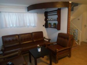 - un salon avec un canapé en cuir et une table dans l'établissement Krisztina Apartman 2-3, à Szigethalom