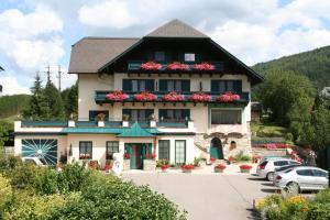 a building with flowers on the balconies in a parking lot at Pension Firn Sepp in Mauterndorf