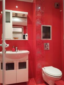 a red bathroom with a toilet and a sink at Уютен апартамент в централната част на Стара Загора in Stara Zagora