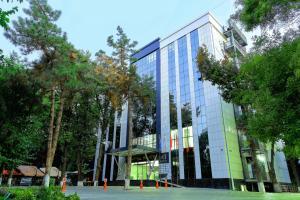 a glass building with trees in front of it at Central Palace Halal Hotel in Tashkent