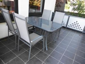 a glass table and chairs on a patio at Zum Roemernest in Würzberg