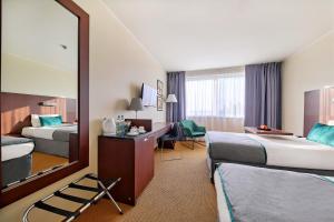 Una habitación de hotel con dos camas y un espejo. en Mercure Warszawa Airport, en Varsovia 81 fotos más
