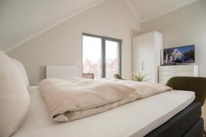a white bedroom with a bed and a window at Ostsee - Appartement Nr 96 "Seehase" im Strand Resort in Heiligenhafen