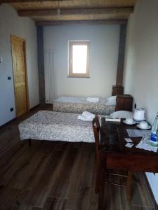 AlpignanoにあるCascina Bucolicaのベッドルーム1室(ベッド2台、テーブル、窓付)