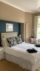 a bedroom with a large white bed with blue walls at The Poplars Guest House in Combe Martin