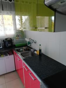 una cocina con armarios rosas y verdes y fregadero en Habitación individual en Tàrrega, en Tàrrega