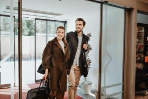 un hombre y una mujer de pie en un aeropuerto con su equipaje en Kolpinghaus Linz, en Linz