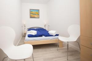 a small bedroom with a bed and two white chairs at Schleiblick App 3 in Rabenkirchen-Faulück