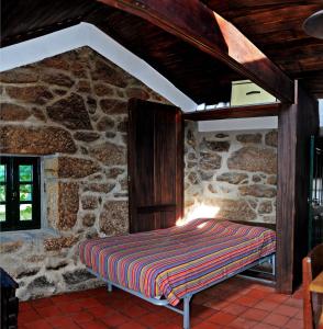 a bed in a room with a stone wall at Casinha da Horta in Soajo