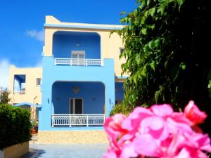 a blue house with a balcony and pink flowers at Apartments Papafotis in Alinda