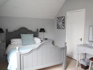 a bedroom with a white bed and white walls at Frasers Guest House in Battlesbridge