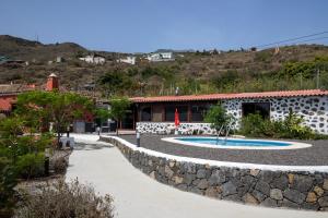 un complejo con una pared de piedra alrededor de una piscina en CASA RURAL LOS DRAGUITOS 2, en Santa Cruz de la Palma