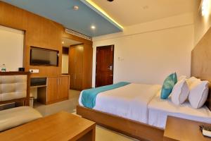Schlafzimmer mit einem Bett, einem Schreibtisch und einem TV in der Unterkunft Hotel Wilton in Sultan Bathery
