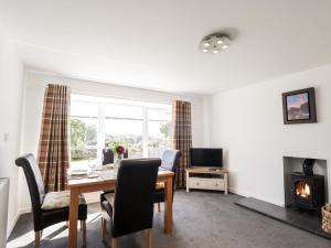 a living room with a table and chairs and a fireplace at Clyne Cottage in Elgin