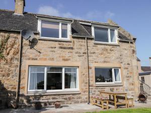 Casa de piedra con 3 ventanas y mesa de picnic en Clyne Cottage, en Elgin