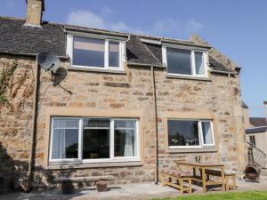 a stone house with three windows and a picnic table at Clyne Cottage in Elgin