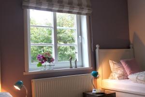una camera da letto con finestra e vaso di fiori di Dat Stadthus a Wyk auf Föhr