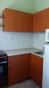 a kitchen with wooden cabinets and a sink and a refrigerator at Szatmári Vendégház in Balatonlelle