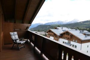 a chair on a balcony with mountains in the background at Ski in out! Gemütliche Dachgeschosswohnung in Königsleiten