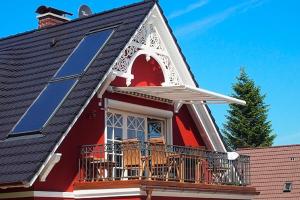 a red house with solar panels on the balcony at Jolle in Zingst