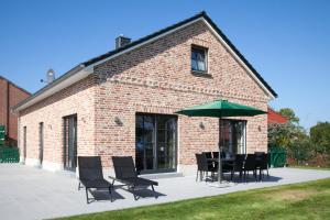 - un bâtiment en briques avec une table, des chaises et un parasol dans l'établissement Ostseehaus 1 - 51526, à Westermarkelsdorf